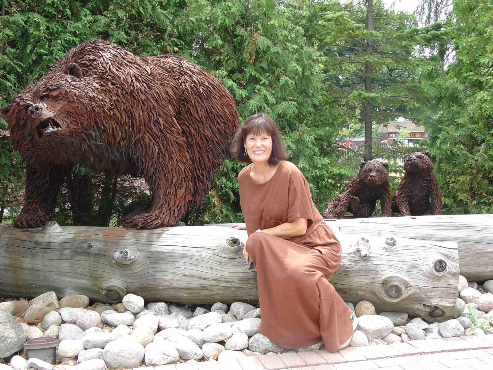 Artist Hilary Clarke Cole seated next to a metal statue of a growling bear